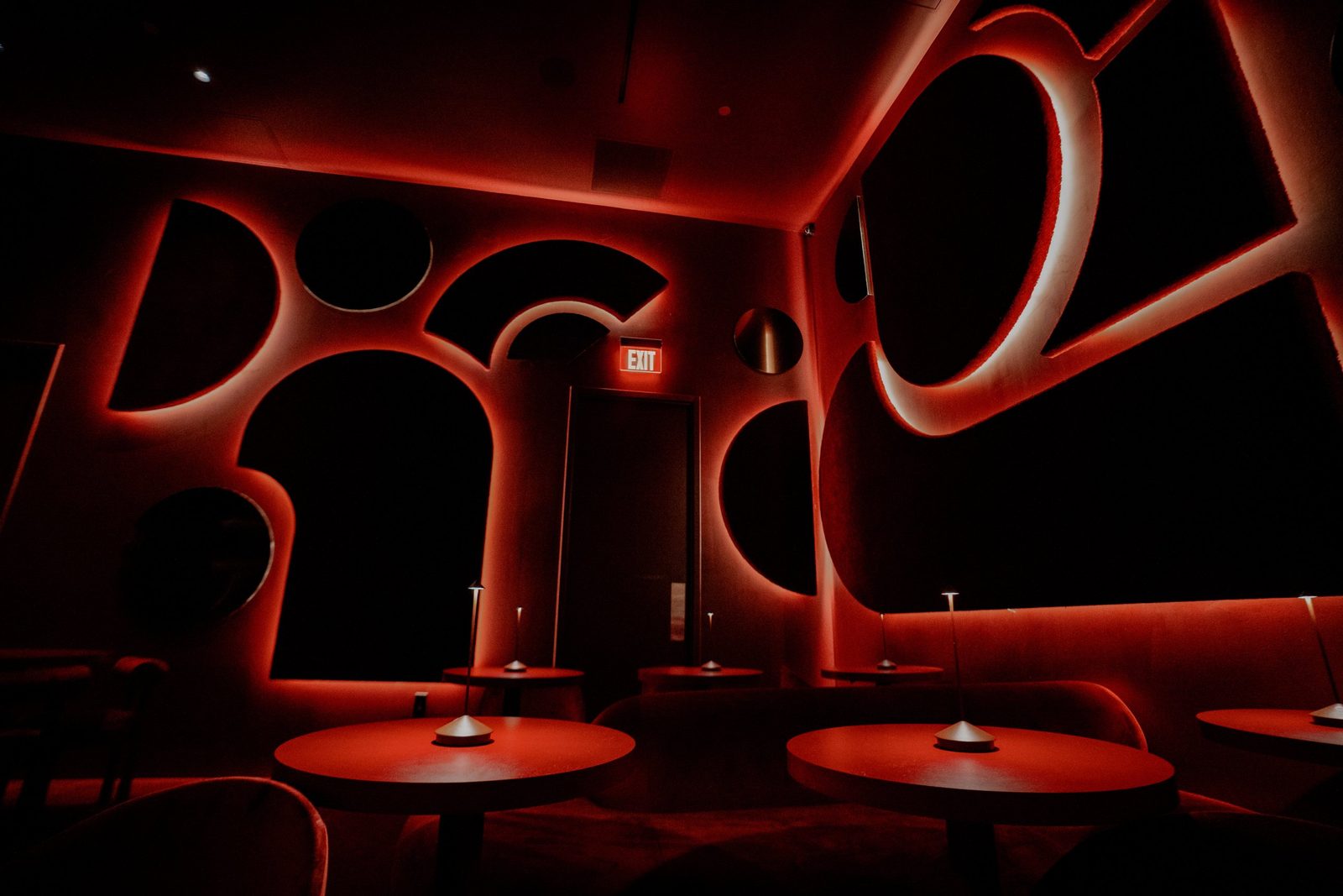 Alter Ego's lounge, with red-lit cutouts in the walls and small round tables with table lamps